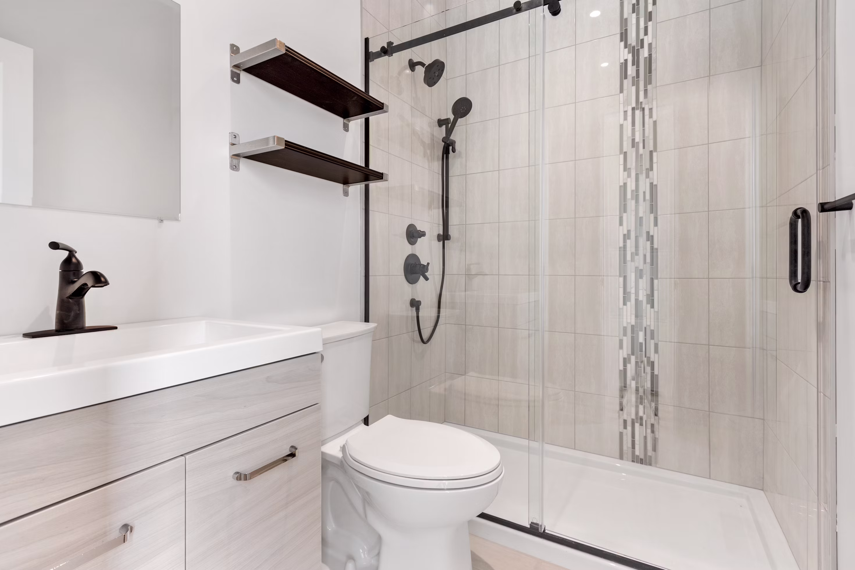 Remodeled bathroom with sliding-glass shower, accent tile inlay and floating vanity