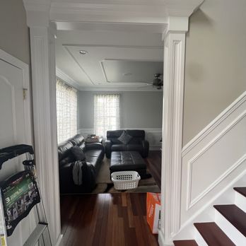 Sunlit room with black leather furniture, hardwood flooring, and white wainscoting walls