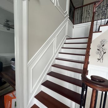 Modern staircase with dark wood steps, white risers, and white wainscoting on walls