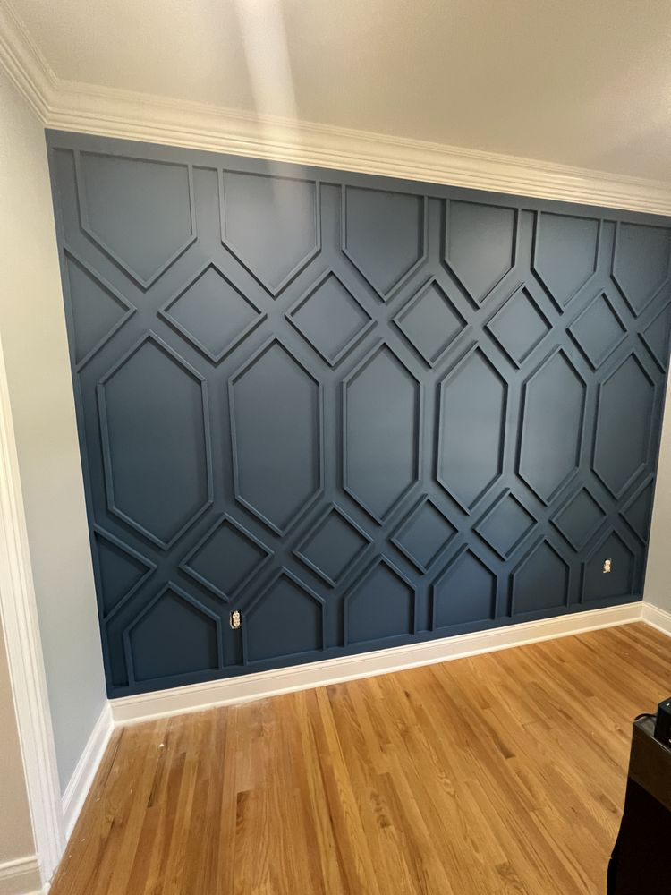 Dark blue geometric wall paneling with cream trim above hardwood floor