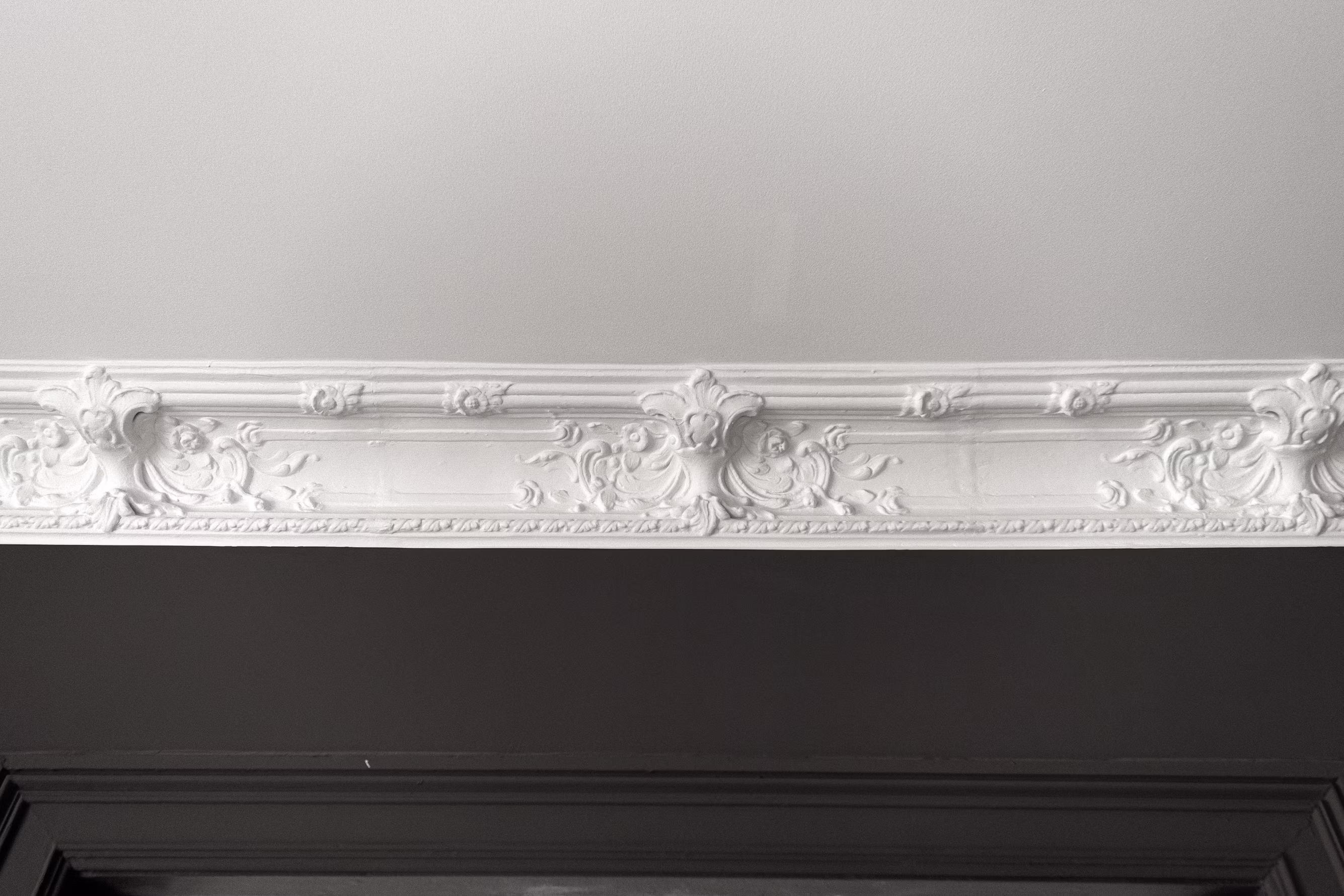 Ornate hand-finished crown moulding meeting the ceiling above a dark wall