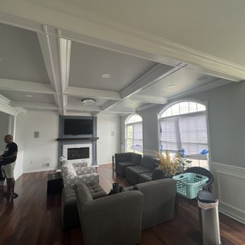 Modern living room with gray walls, coffered ceiling, fireplace, curved sectional sofa, and large windows